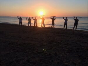 Tai Chi Säbelform einer Gruppe am Strand vor Sonne